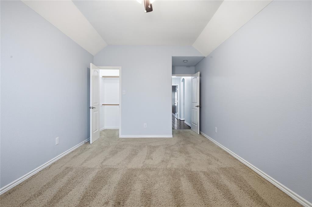 10001 Thurman Road Fort Worth, TX 76244 - Photo 27 of 40 Carpeted room featuring light blue walls, white trim, a vaulted ceiling, and an open closet with built-in shelving