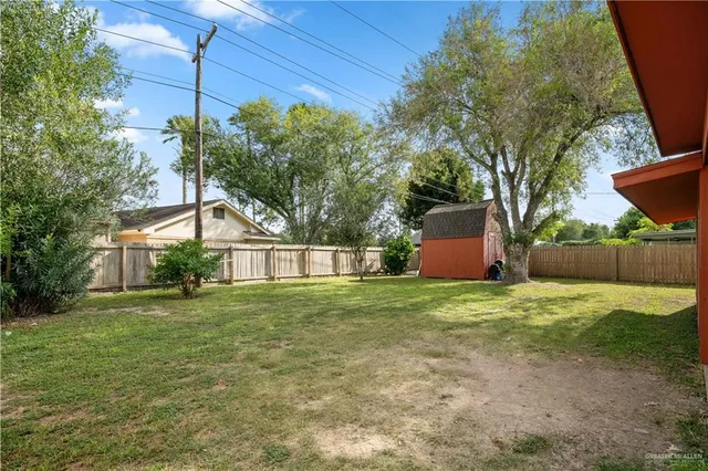 a backyard of a house with plants and large tree