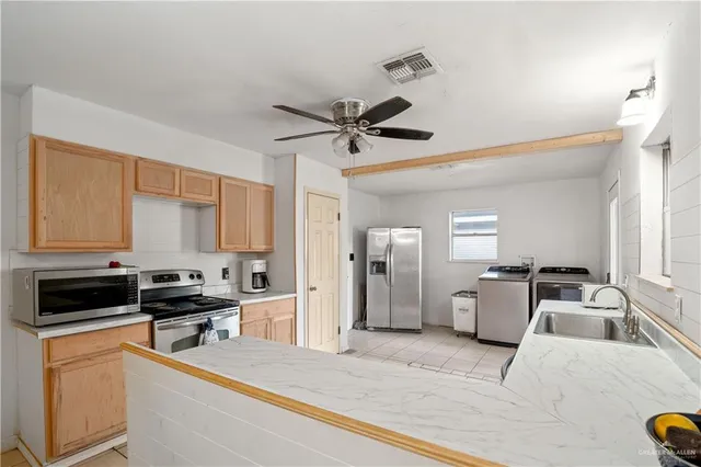 a kitchen with stainless steel appliances kitchen island granite countertop a sink cabinets and refrigerator