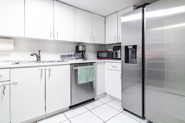 a kitchen with stainless steel appliances granite countertop a refrigerator a sink a stove and white cabinets