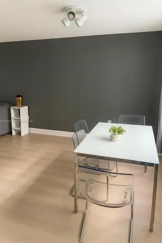 a room with a table chair and white wooden cabinets