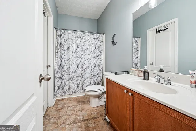 a bathroom with a sink a toilet and shower curtain