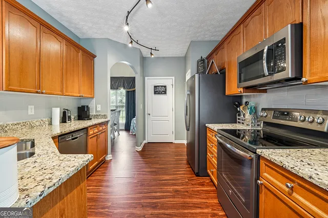 a kitchen with stainless steel appliances granite countertop wooden cabinets a stove top oven a sink and dishwasher