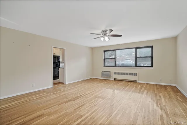 a view of an empty room with a window and wooden floor