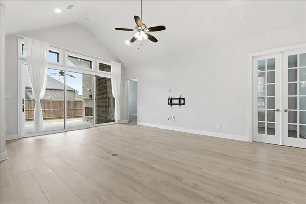 a view of an empty room with a window and wooden floor