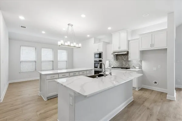 a kitchen with a sink a stove a refrigerator and white cabinets