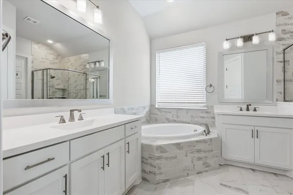 a bathroom with a granite countertop bathtub sink double and mirror