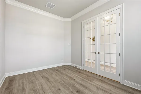 an empty room with wooden floor closet and windows