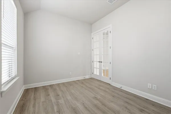 an empty room with wooden floor and windows