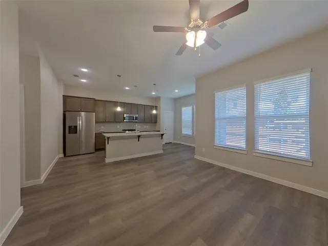 a view of an empty room with kitchen view and a window