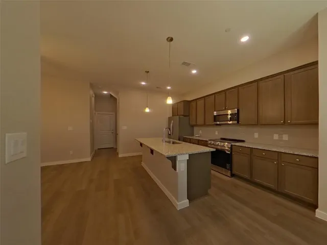 a large kitchen with stainless steel appliances a sink and cabinets