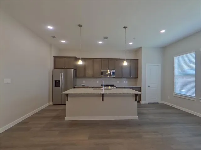 a view of kitchen with stainless steel appliances wooden floor and window