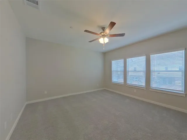 an empty room with a window and a ceiling fan