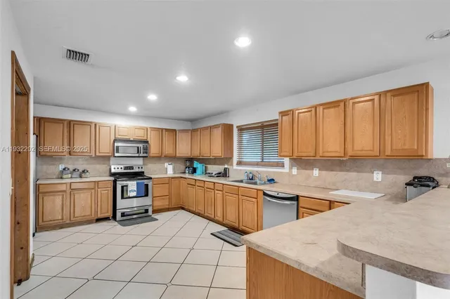 a kitchen with stainless steel appliances granite countertop a stove top oven a sink a refrigerator and white cabinets