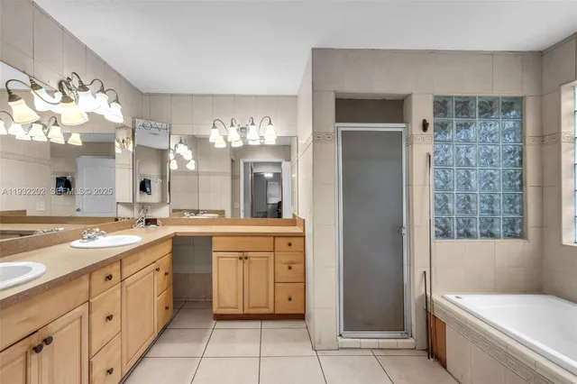a large bathroom with a double vanity sink a large mirror and a bathtub