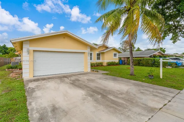 a view of a house with a yard and palm trees