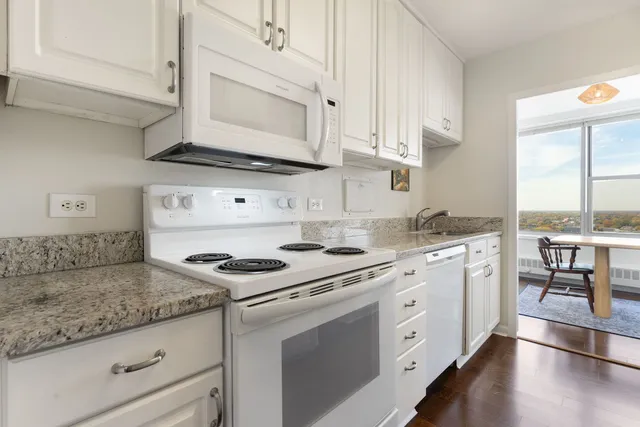 a kitchen with granite countertop white cabinets and white appliances