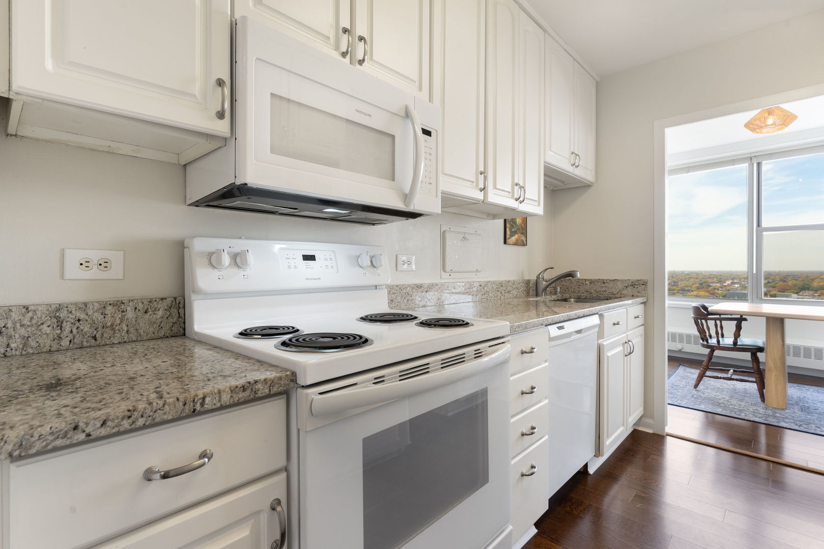 3900 North Lake Shore Drive, Unit 18F Chicago, IL 60613 - Photo 14 of 22 a kitchen with granite countertop white cabinets and white appliances