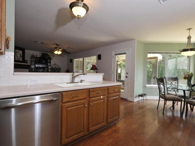8121 Siringo Pass Austin, TX 78749 - Photo 5 of 9 Kitchen featuring wood finish cabinets, stainless steel dishwasher, light countertops, dark wood finished floors, and a peninsula