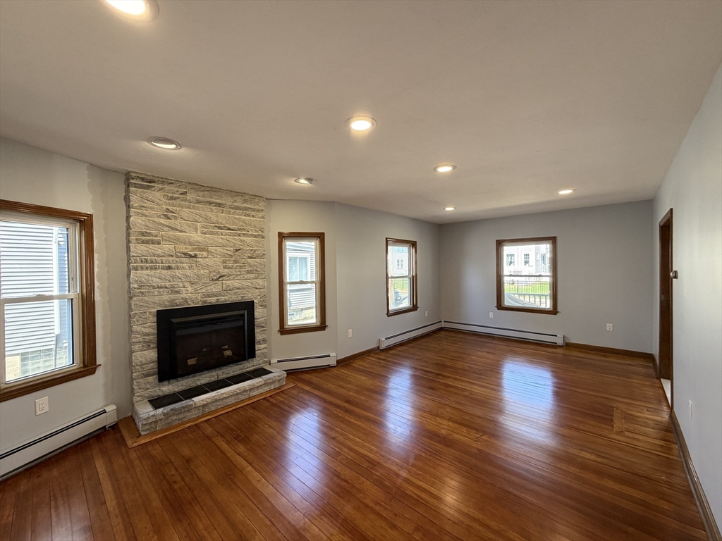117 Merrymount Road, Unit 1 Quincy, MA 02169 - Photo 11 of 12 an empty room with wooden floor fireplace and windows