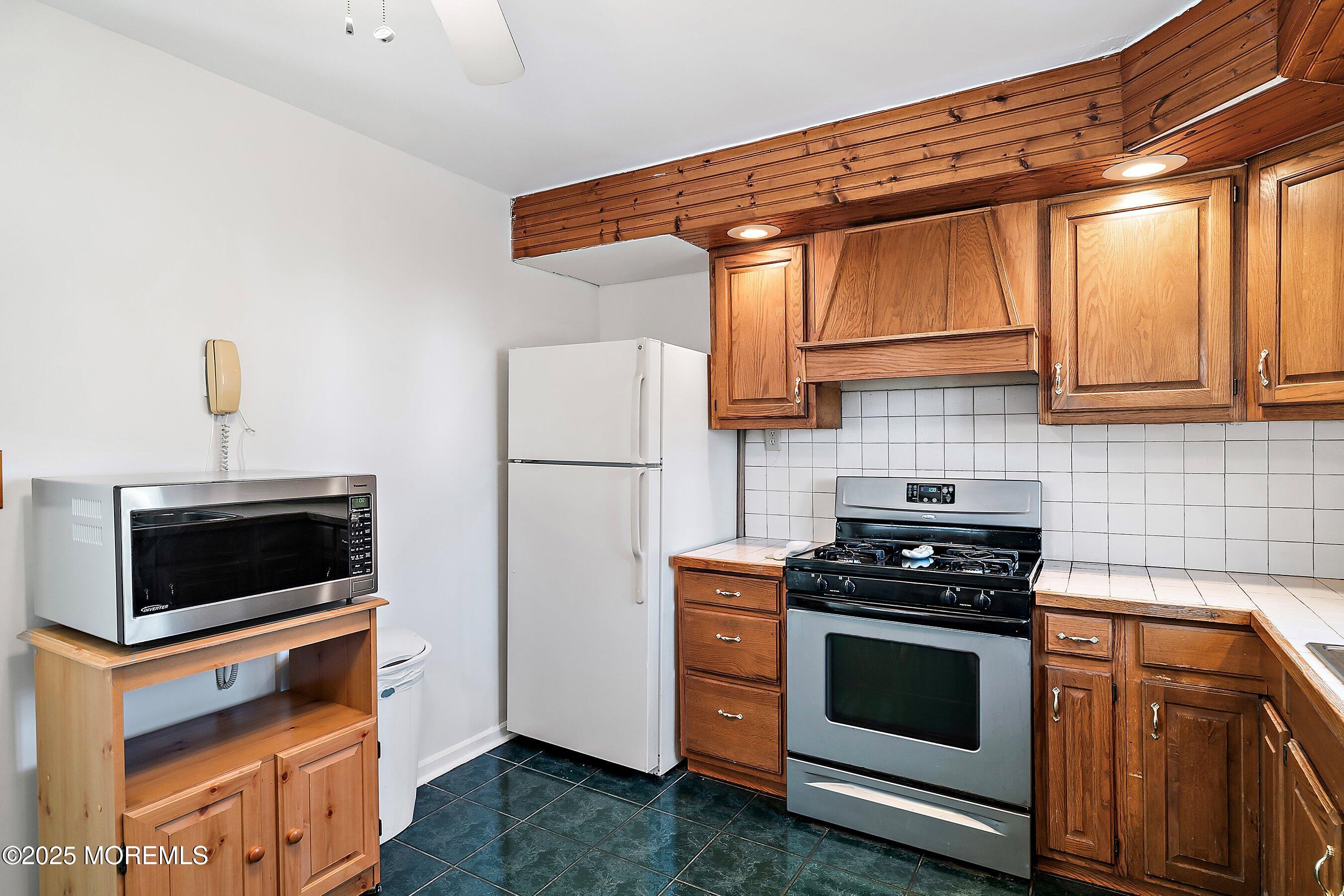 501 Stone Road Union Beach, NJ 07735 - Photo 8 of 30 a kitchen with stainless steel appliances a stove a microwave and a refrigerator