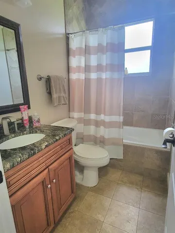 a bathroom with a granite countertop sink a toilet a mirror and shower