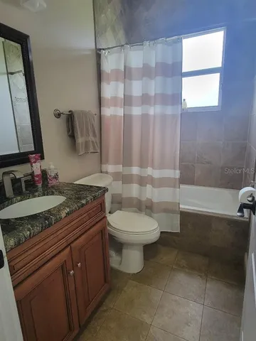 a bathroom with a granite countertop sink a toilet a mirror and shower
