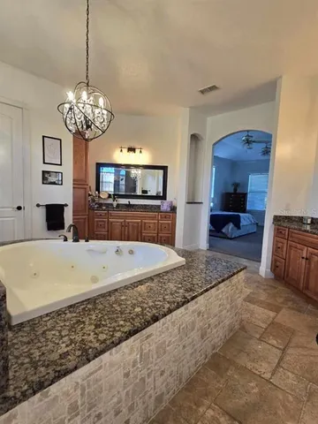 a spacious bathroom with a granite countertop sink a large mirror and a bathtub
