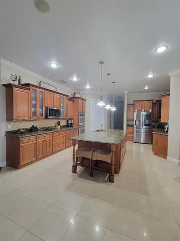 a large kitchen with kitchen island a sink a counter and chairs