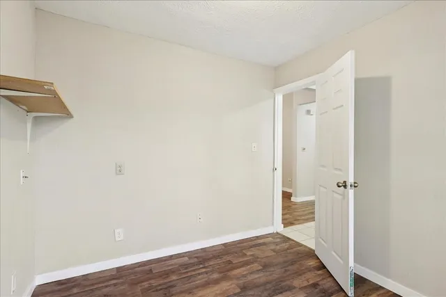 an empty room with wooden floor and a bathroom