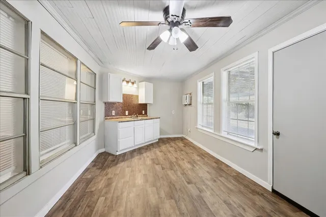a large white kitchen with wooden floor a sink a refrigerator and window