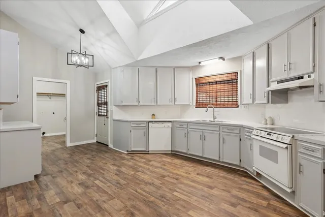 a kitchen with stainless steel appliances granite countertop a stove a sink dishwasher a refrigerator and white cabinets with wooden floor