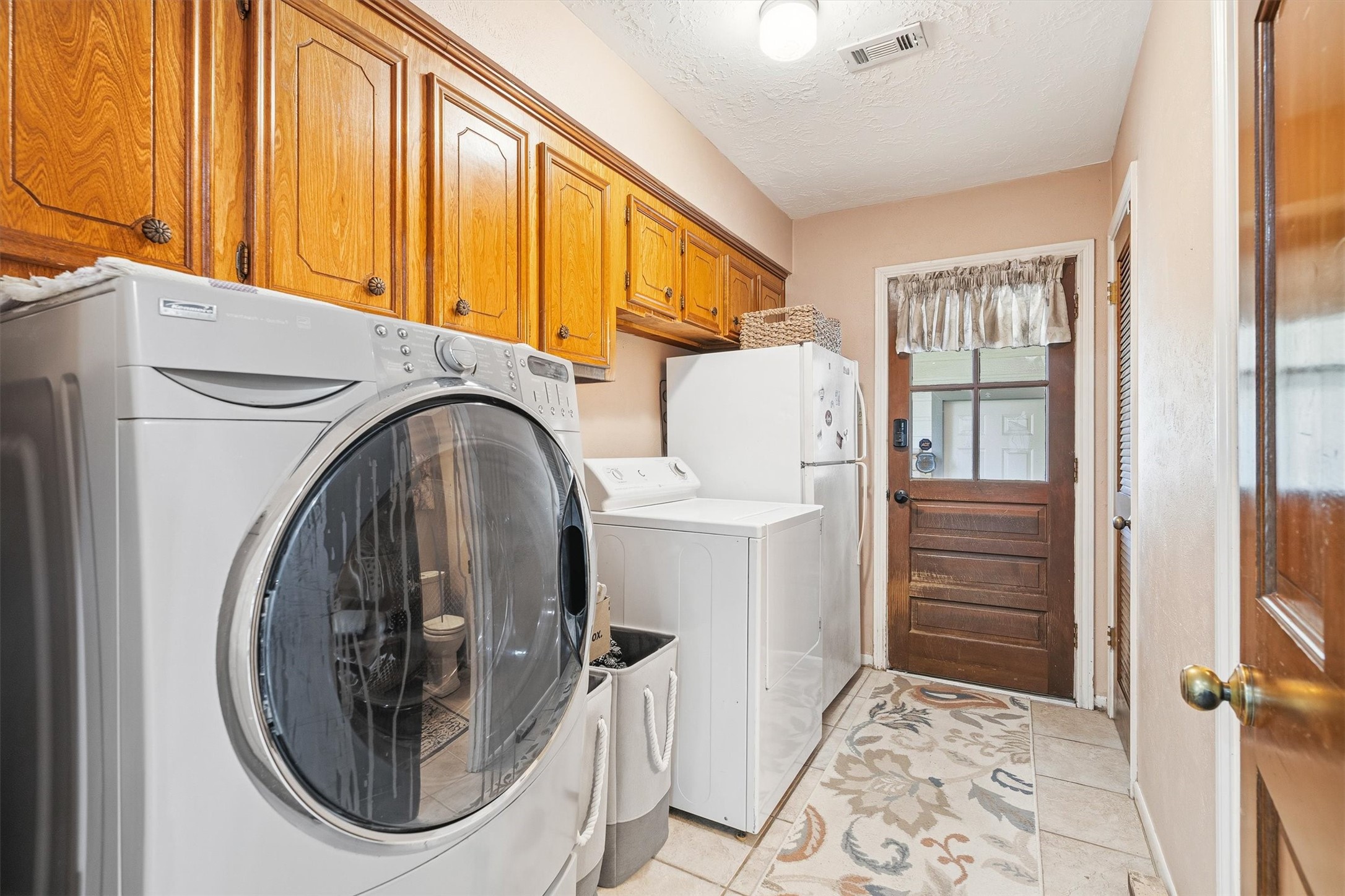 826 North Rivershire Drive Conroe, TX 77304 - Photo 31 of 46 A dedicated laundry room with upper cabinetry, tile flooring, and exterior door access makes everyday living in this home genuinely convenient.