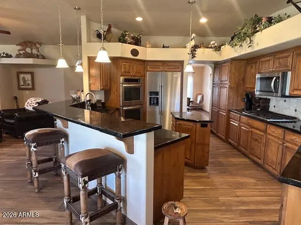 a kitchen with stainless steel appliances kitchen island granite countertop a table chairs sink and cabinets