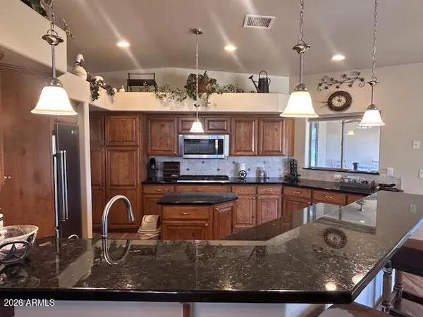a kitchen with kitchen island granite countertop a stove a sink a counter space cabinets and a chandelier