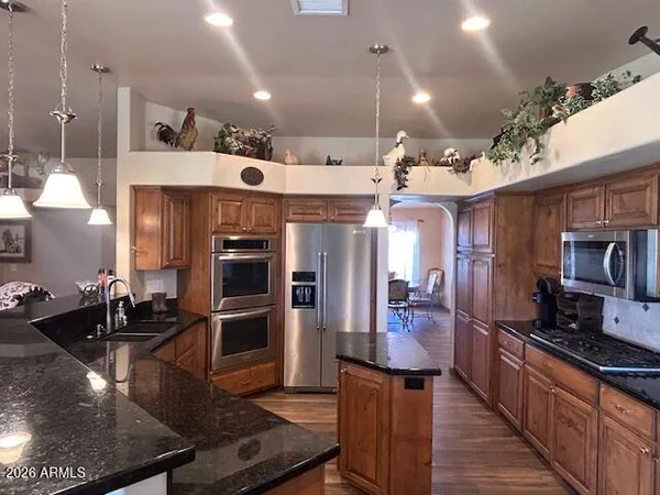 a kitchen with stainless steel appliances kitchen island granite countertop a stove refrigerator and cabinets