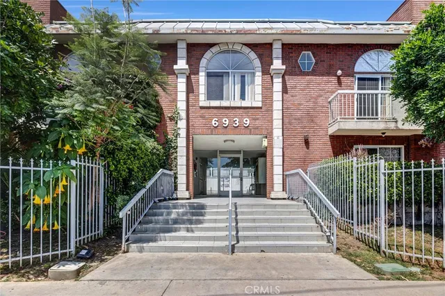 a view of a brick house with large windows and a small yard