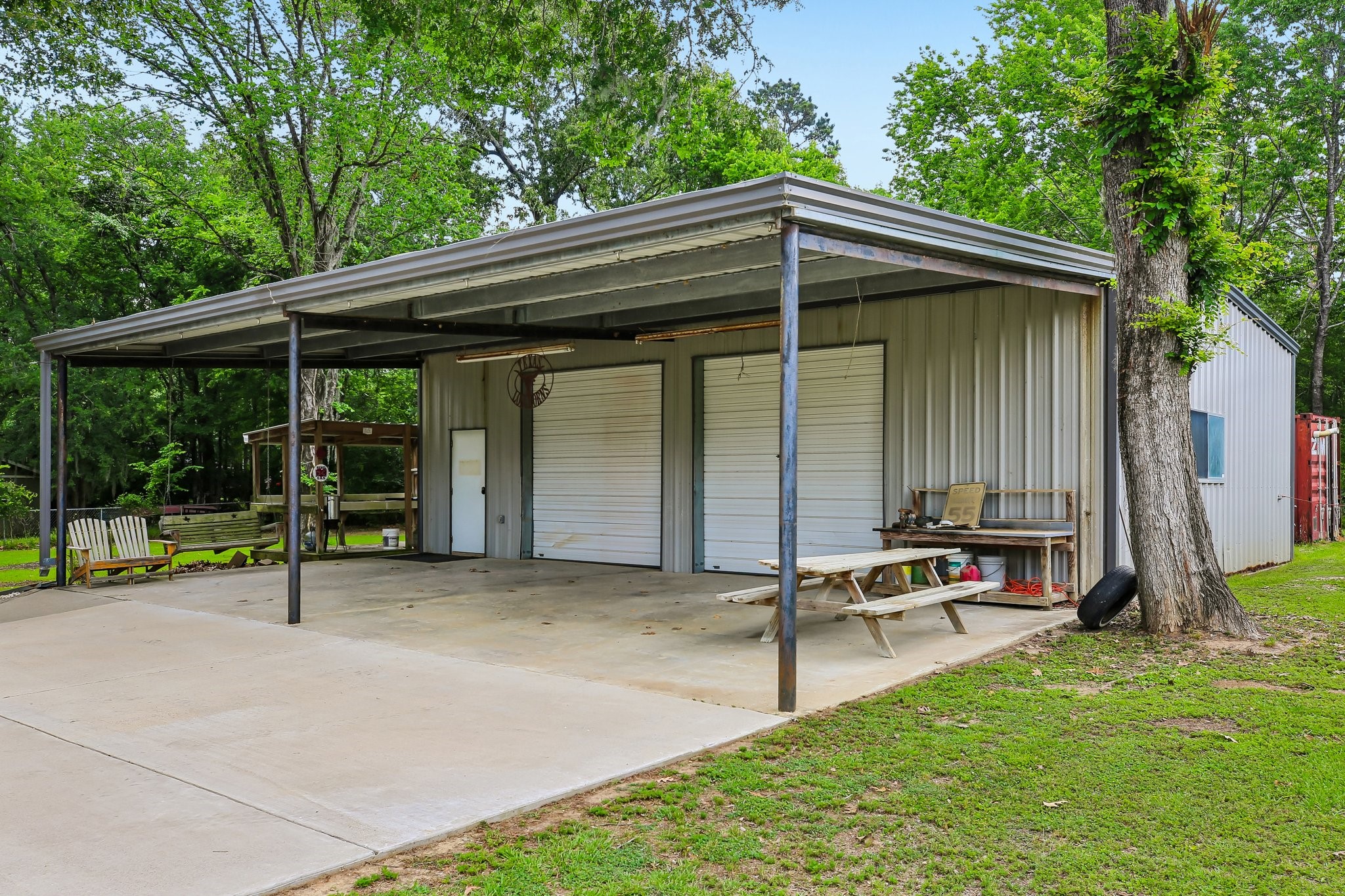 164 Frank Road Trinity, TX 75862 - Photo 7 of 20 A dream for hobbyists or professionals, this massive workshop features dual roll-up doors and a large covered carport area, providing a professional-grade space for any project.