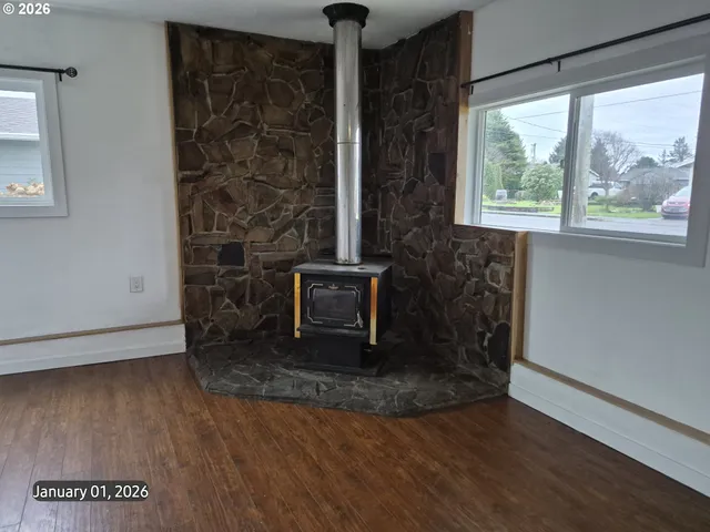an empty room with wooden floor fireplace and windows