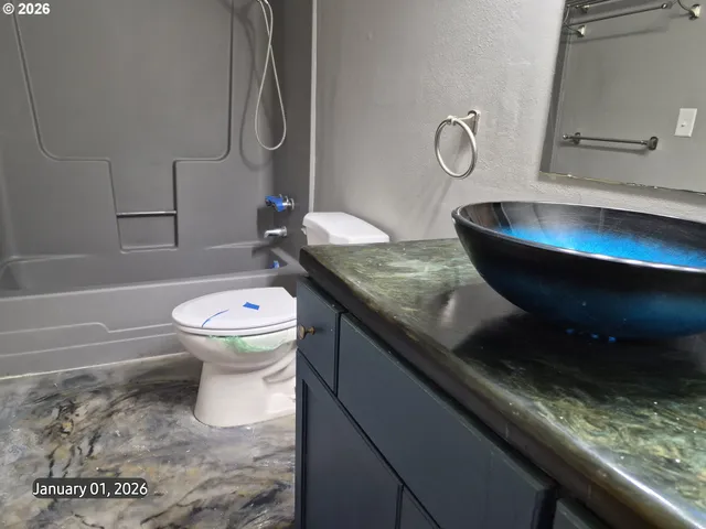 a bathroom with a granite countertop toilet sink and mirror