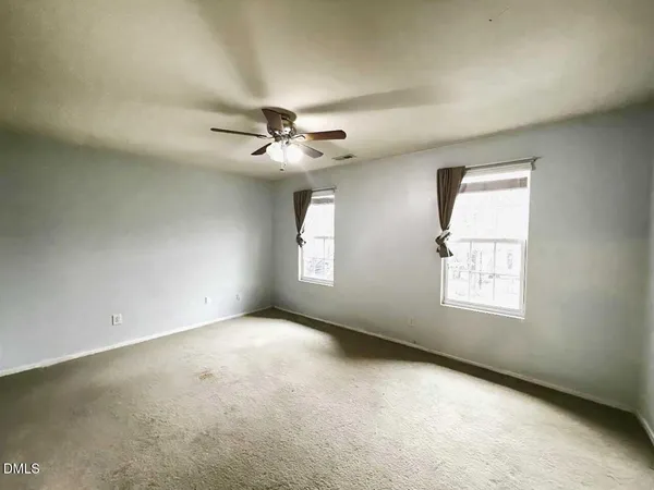 an empty room with a window and a fan