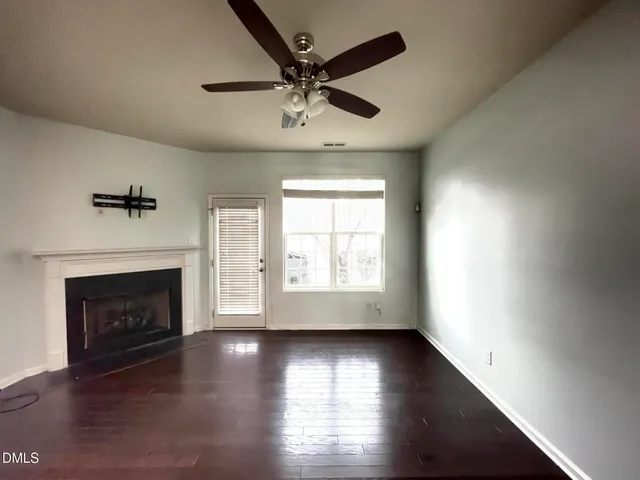 an empty room with fireplace wooden floor and windows