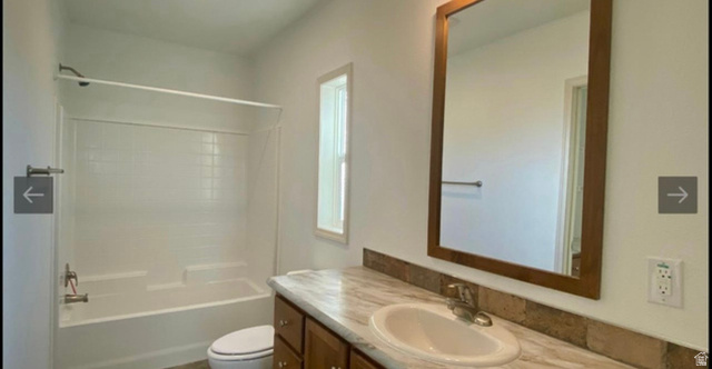 289 West Center Street Hinckley, UT 84635 - Photo 5 of 13 Bathroom featuring a vanity with a white oval sink, wood-finish cabinetry, and a framed mirror