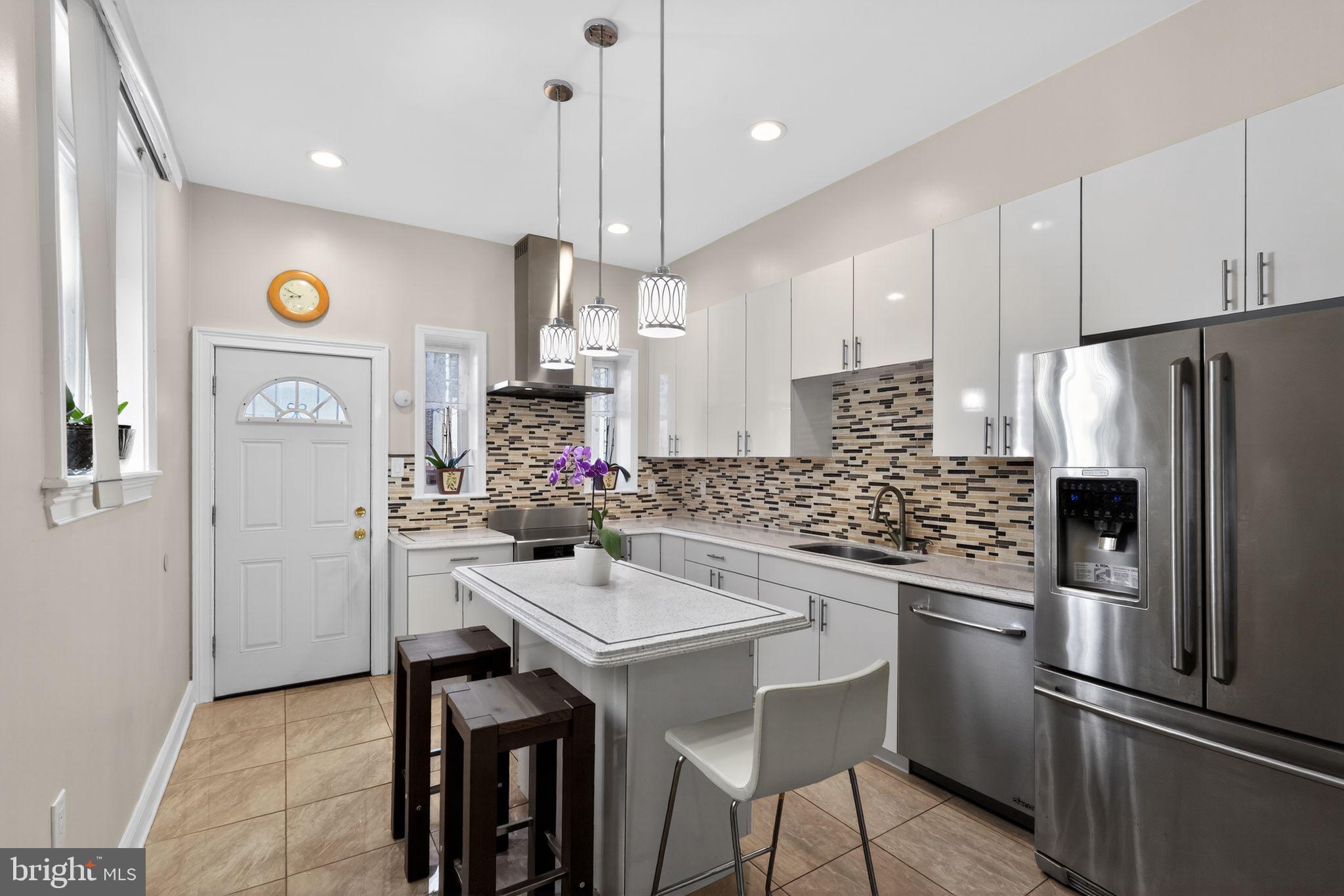 2515 South 16th Street Philadelphia, PA 19145 - Photo 13 of 29 a kitchen with stainless steel appliances kitchen island a table chairs in it and wooden floors