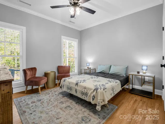 a bedroom with a bed a couch and two windows