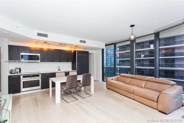 a living room with furniture a flat screen tv and kitchen view