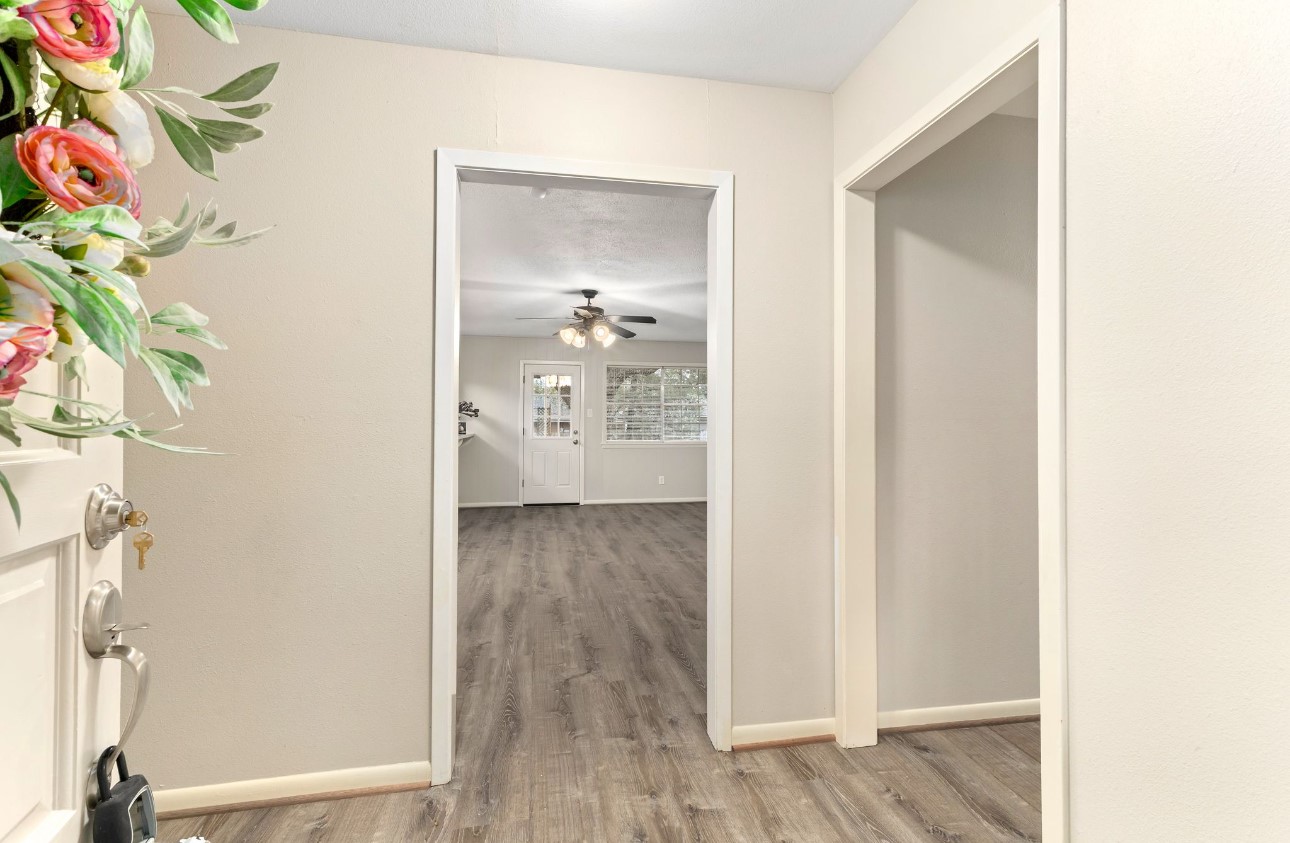 a view of a hallway with wooden floor and a bathroom