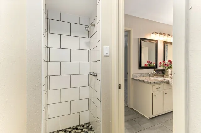 a bathroom with a granite countertop sink a mirror and shower