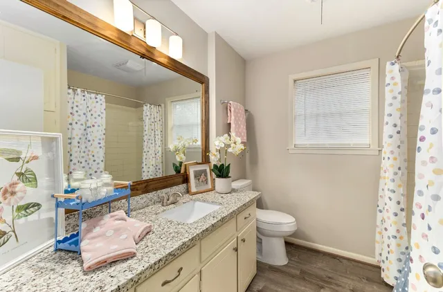 a bathroom with a granite countertop sink a toilet and a mirror