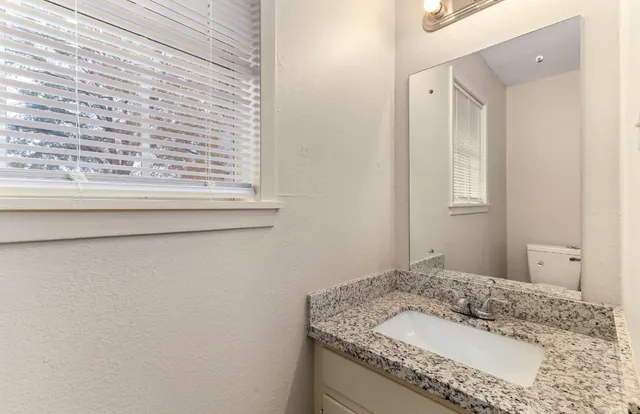 a bathroom with a granite countertop sink and a mirror